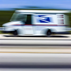 USPS mail truck going so fast down highway that it appears blurred